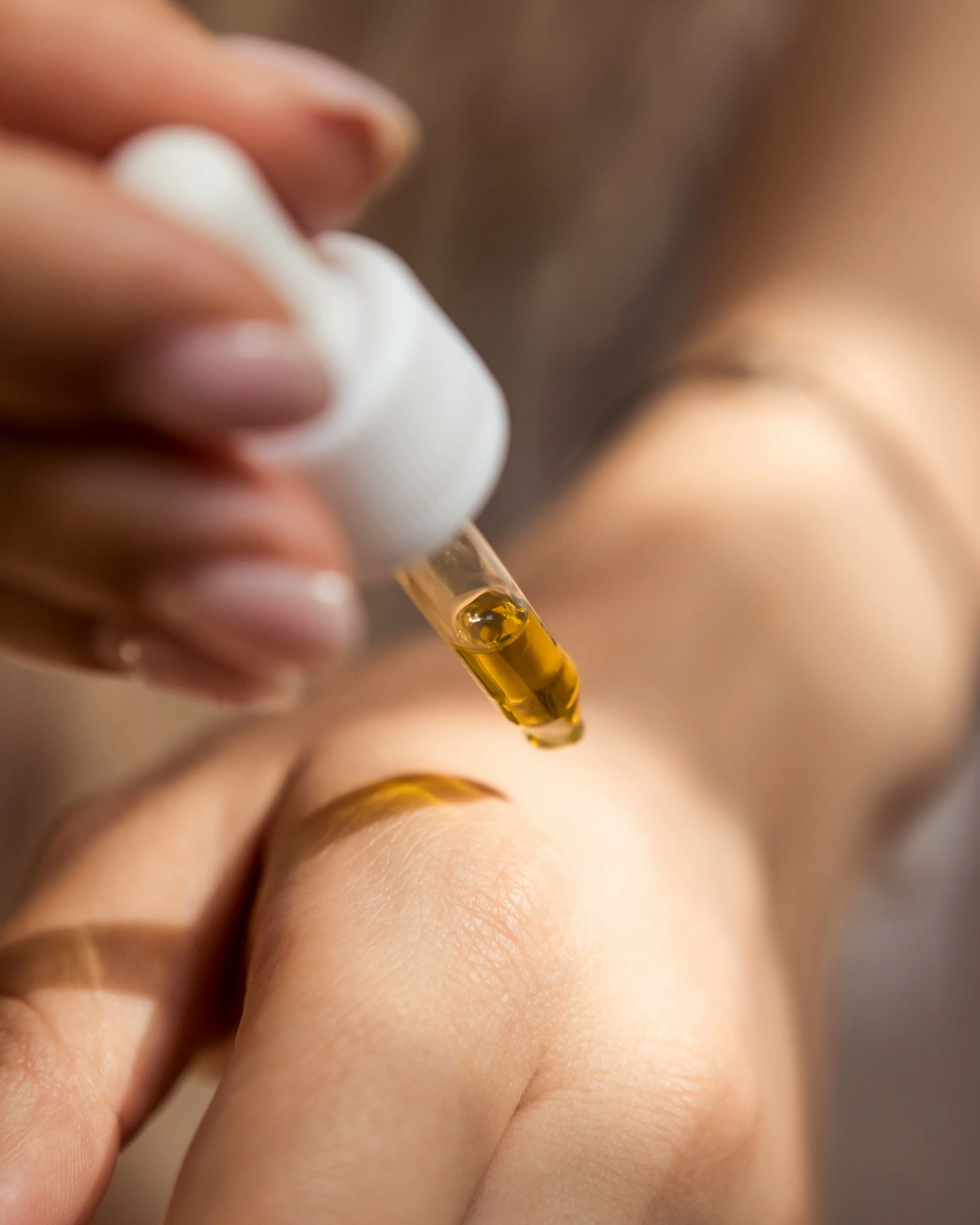 Pipette d'huile de soin appliquée sur la peau d'une main — cosmétique naturelle