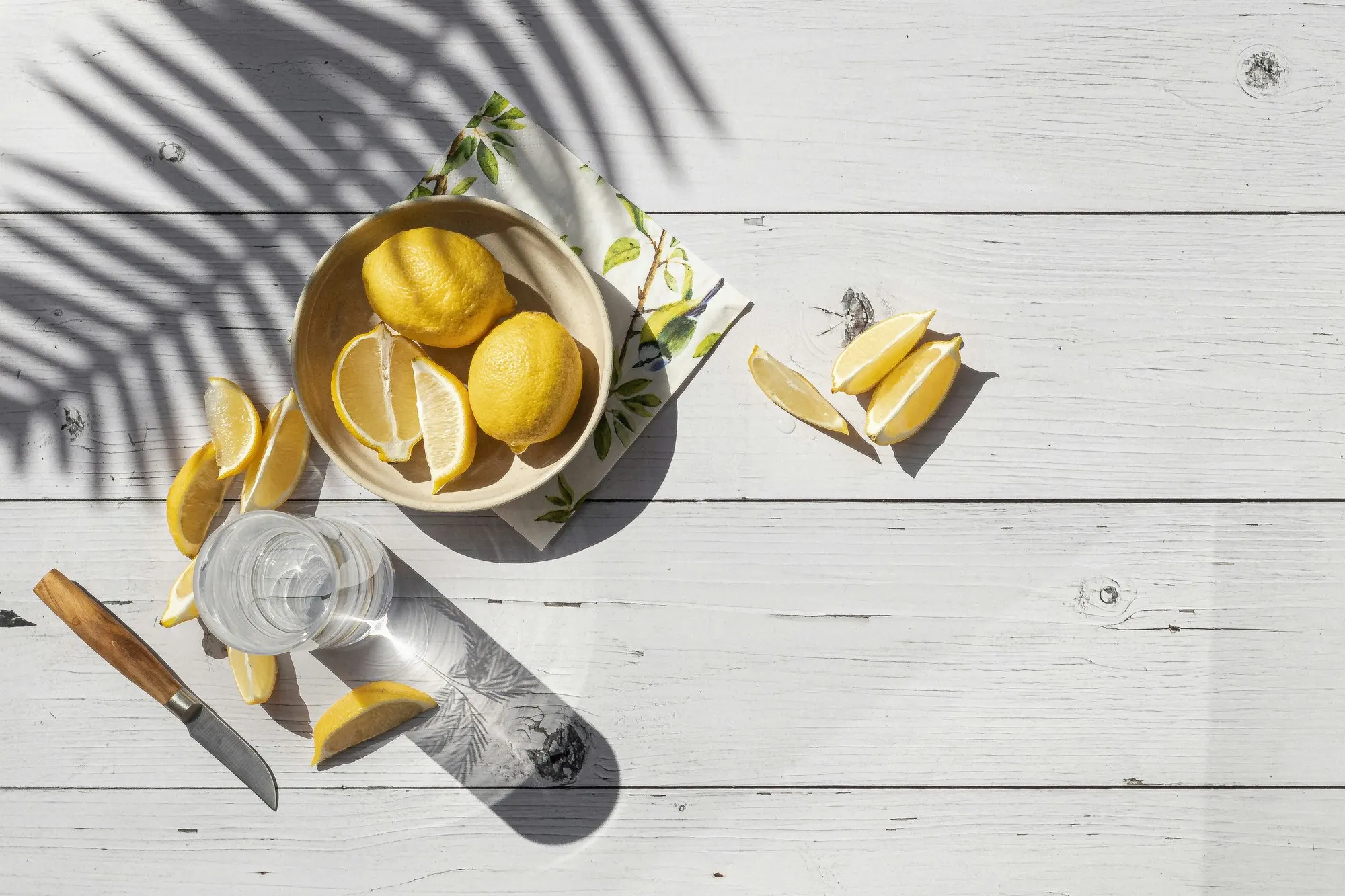 Citrons coupés, quartiers et couteau sur bois clair — conserver un citron entamé