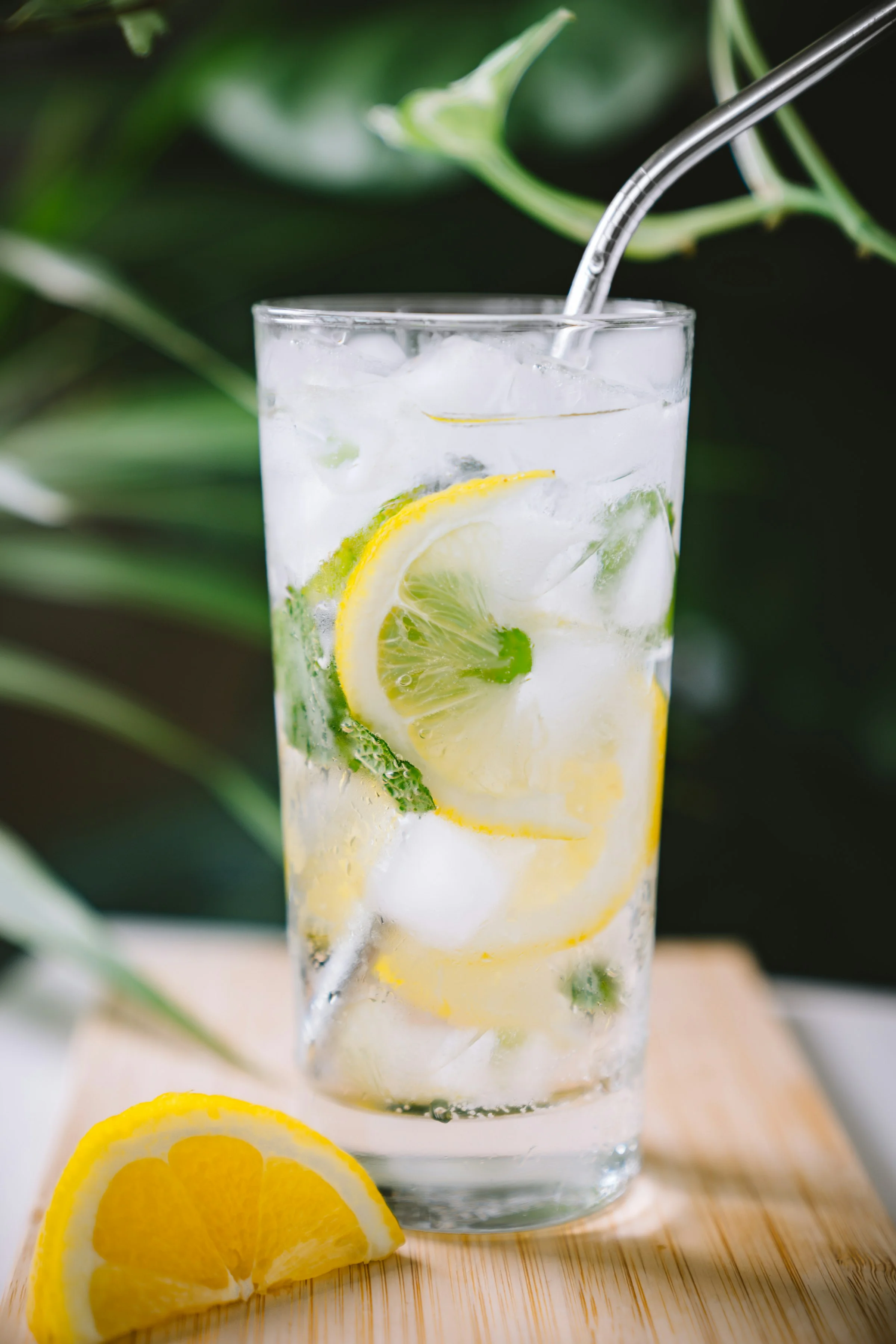 Verre d'eau citronnée avec tranches et glaçons, sur planche en bois