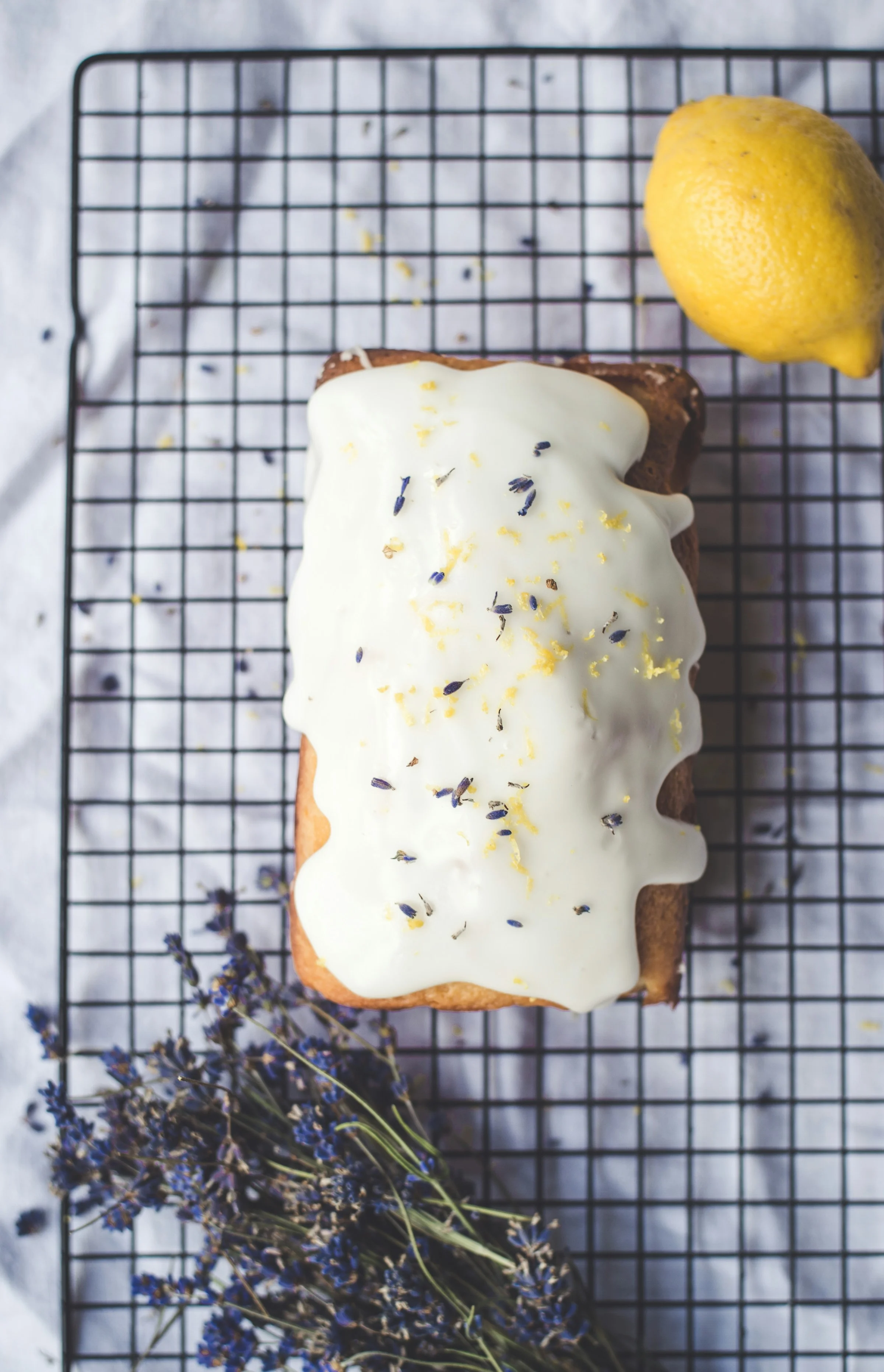 Cake nappé d'un glaçage au citron blanc et brillant, zestes et lavande sur une grille