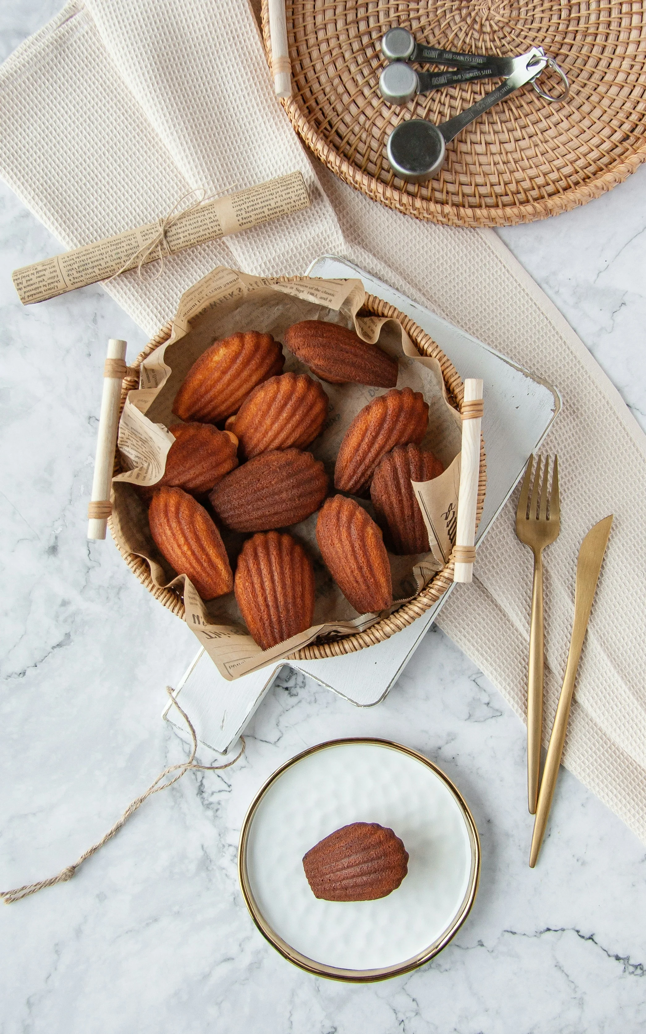 Madeleines au citron dorées dans un panier sur marbre clair