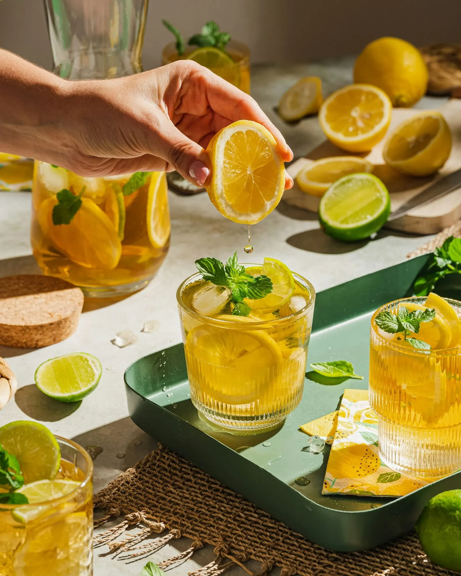 Main pressant un demi-citron au-dessus d'un verre de citronnade, goutte de jus en suspension